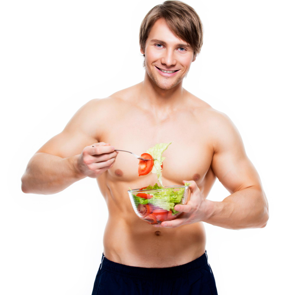 Young happy muscular man eating salad white wall